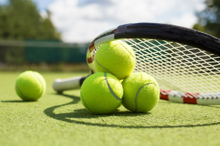 49750172 - tennis balls and racket on the grass court